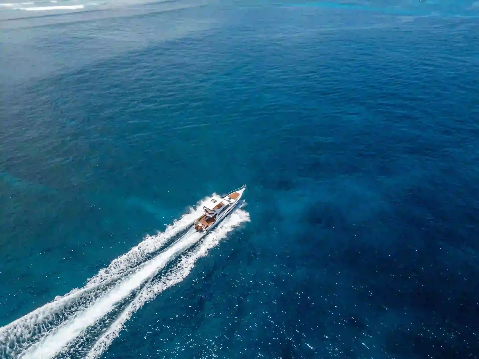 A yacht leaving a long white wake across deep blue water