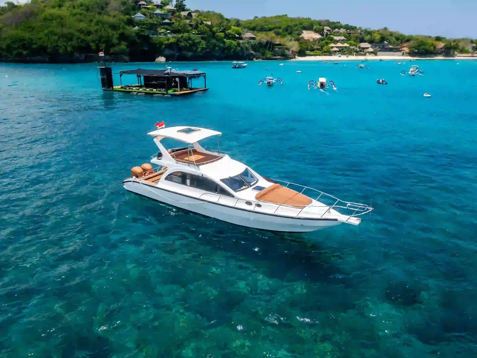 Aerial view of a private motor yacht anchored in turquoise water off a Bali island coast