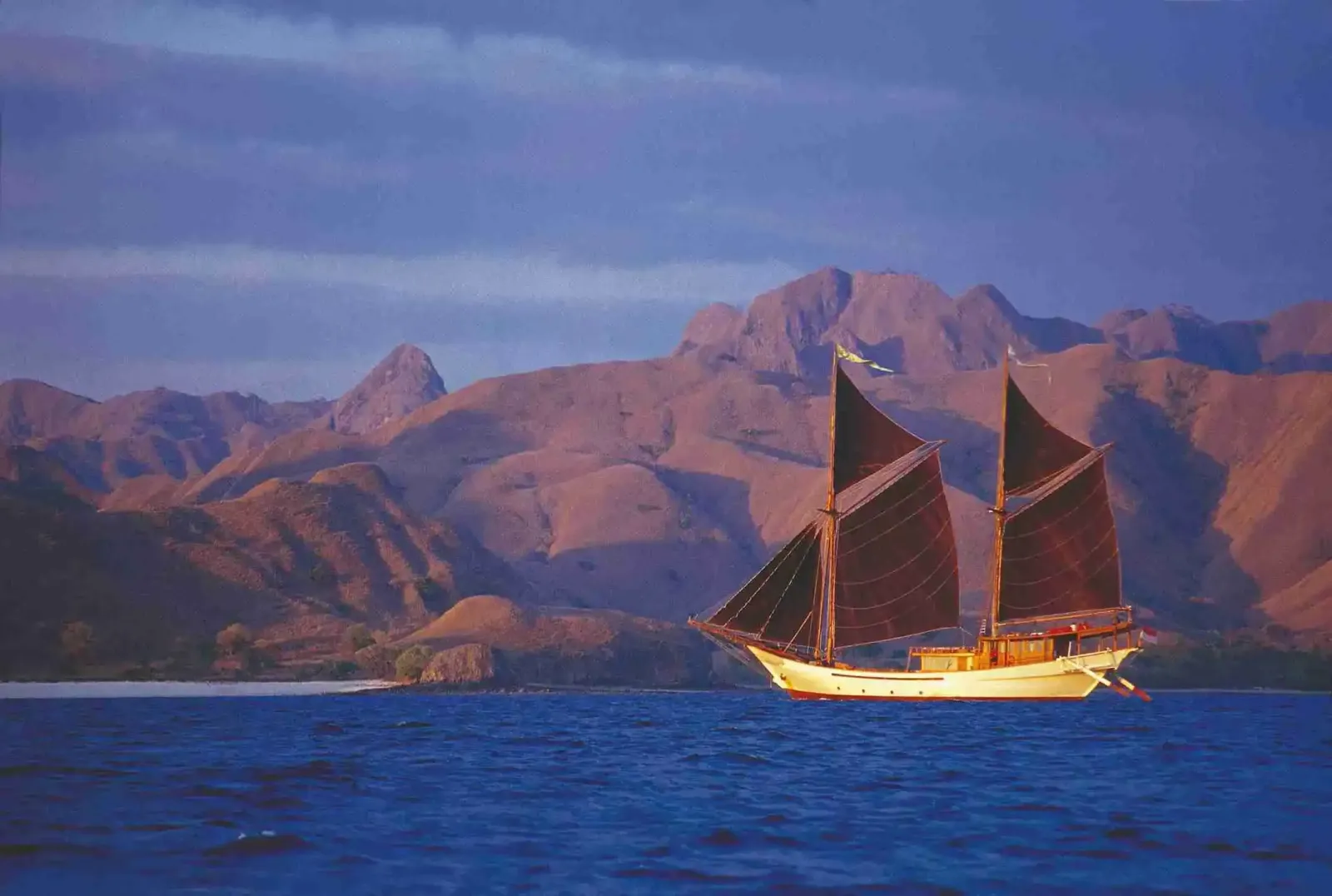 A phinisi under sail at dusk