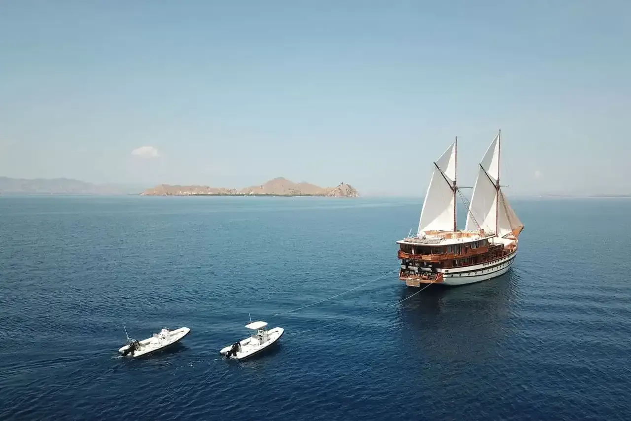 A phinisi at anchor with two tenders alongside