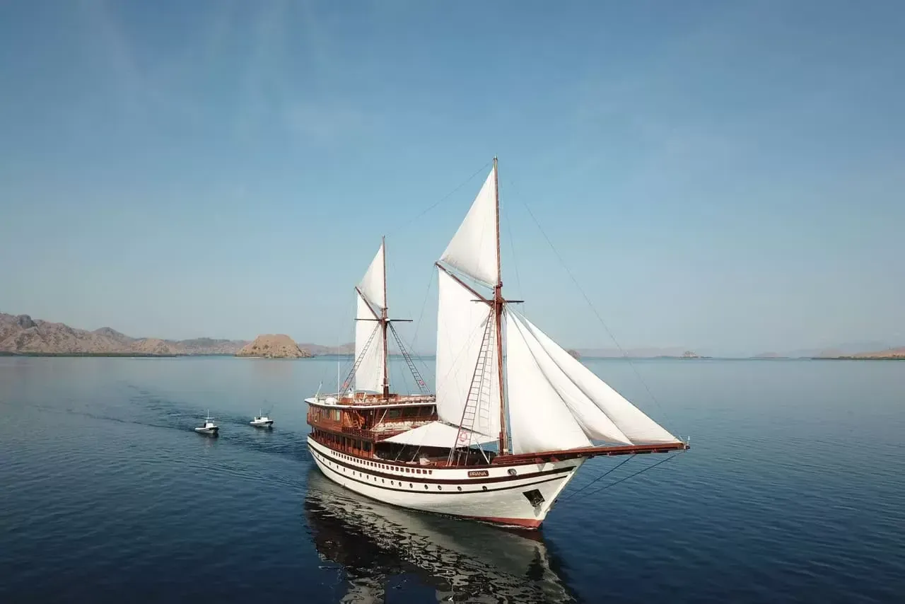 A phinisi schooner under full sail on calm water