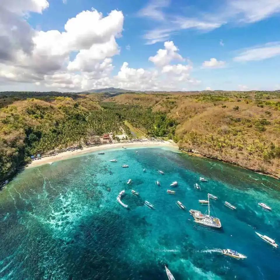 Aerial view of Crystal Bay on Nusa Penida with boats anchored over clear turquoise water