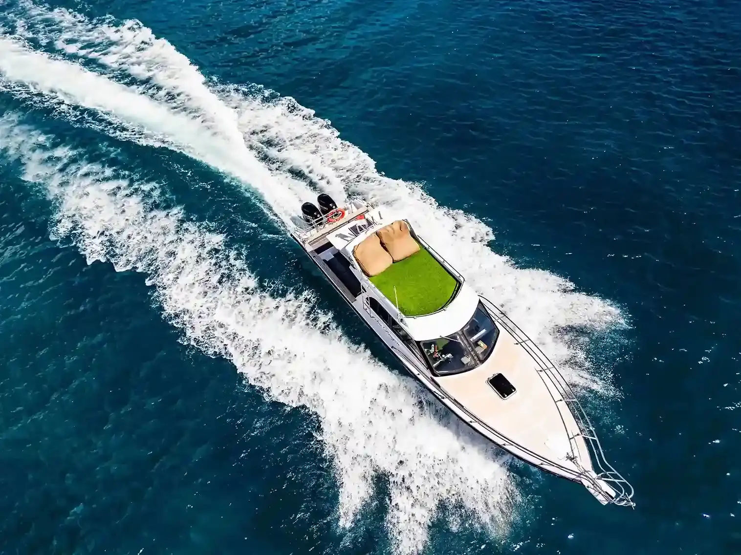 Aerial view of a sport yacht cutting a white wake through deep blue water