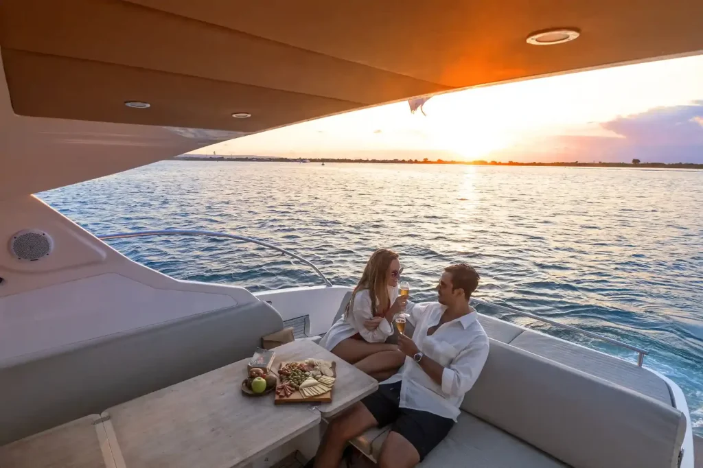 A couple sharing a platter on a yacht deck at sunset