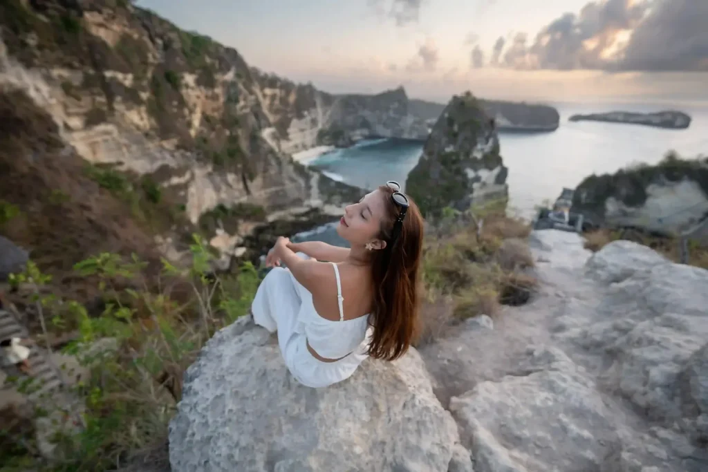 A traveller sitting on a cliff edge above the Nusa Penida coast